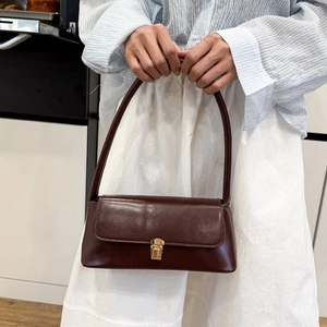 Retro dark brown leather baguette underarm bag with gold clasp shown on a model's arm