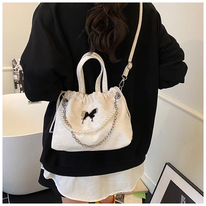Detail of white drawstring bag with silver butterfly charm and decorative pearl chains