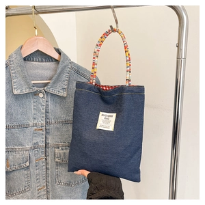 Détail du sac cabas en jean avec poignées tressées colorées et doublure à carreaux rouges