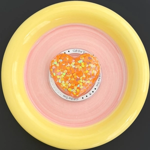 Detail of heart-shaped MagSafe phone grip with vibrant orange and yellow glitter sequins