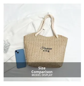 Straw woven tote bag size comparison with a smartphone on white fabric background