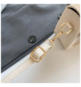 Dettaglio della tracolla in pelle beige con fibbie dorate e trama intrecciata