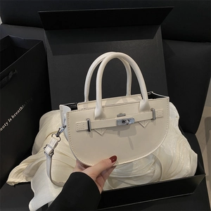 Sac à main élégant blanc cassé avec fermoir rotatif présenté dans une boîte cadeau noire