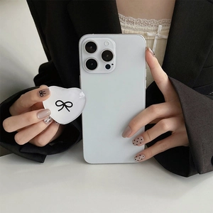 Close-up of heart-shaped phone grip with black bow pattern on a white smartphone