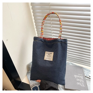 Détail du sac à bandoulière en jean avec poignée tissée colorée et doublure à carreaux