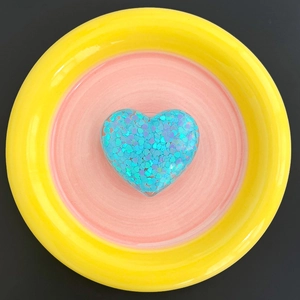 Detail of blue glitter heart phone socket holder on a pink and yellow ceramic dish