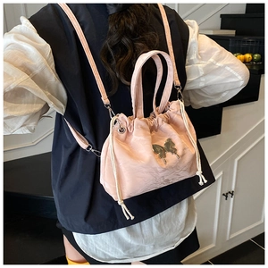 Detail of light pink drawstring handbag with silver butterfly and pearl chain strap