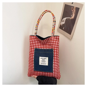 Détail du cabas à carreaux rouges avec poche en denim et poignées tissées
