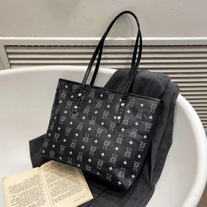 Large black tote bag with white bear prints and gold rivets on a chic grey blazer