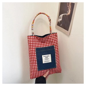 Détail du sac cabas à carreaux rouges avec poche en denim et anses tressées colorées