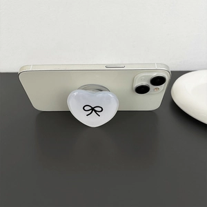 Minimalist heart-shaped phone socket grip with black bow print on a white smartphone