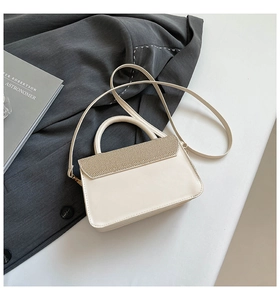 Dettaglio borsa beige in pelle con patta a trama dorata e finiture in metallo lucido