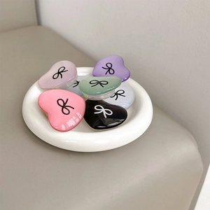 Detailed view of colorful heart-shaped phone grips with bow pattern in a ceramic tray