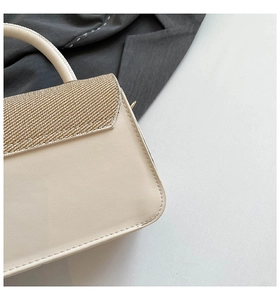 Dettaglio ravvicinato della borsa in pelle crema con trama glitter oro e cuciture fini