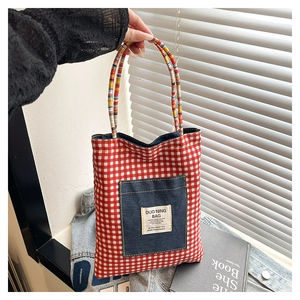 Détail du sac cabas à carreaux rouges avec poche en denim et poignées en corde tressée