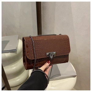 Detail of dark brown crocodile-embossed bag with chain strap and geometric stud lock