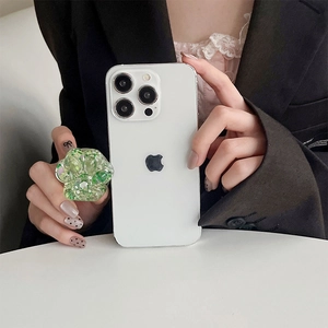 Macro view of a sparkling green cat paw retractable phone socket held by a hand.