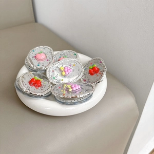 Détail de supports de téléphone fruits pailletés avec cerise et pêche sur base argent