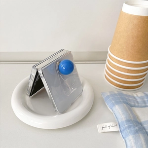 Transparent Samsung Z Flip case with blue sphere ring holder on white ceramic plate