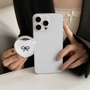 Close-up of white heart-shaped phone grip with bow design held by hand on white case
