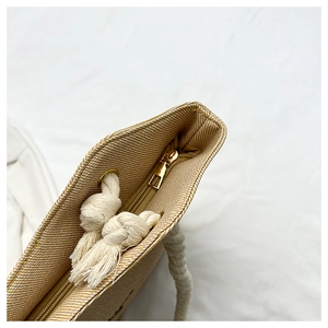 Detail of woven straw tote bag featuring secure gold metal zipper and cotton rope handles