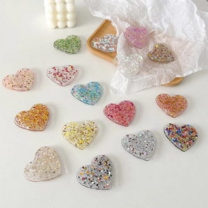 Glitter heart-shaped collapsible phone grip stand in various colors on white background
