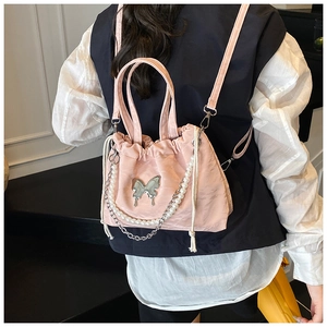 Detail of pink drawstring backpack with silver butterfly charm and pearl chain accent