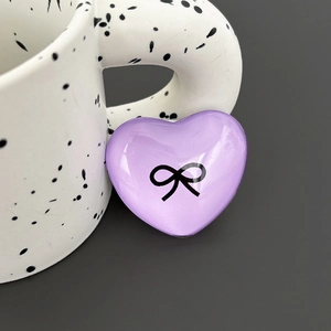 Detailed close-up of a purple heart-shaped phone grip featuring a black bow design