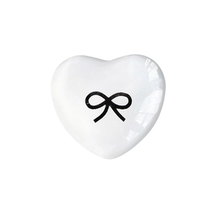 White heart-shaped ceramic phone grip with black bow print and glossy glazed finish
