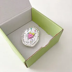 Détail d'une breloque raisin rose pailletée dans un support ovale en métal