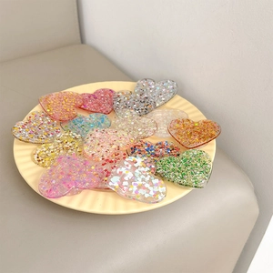 Assorted heart resin phone grips with glitter and sequins in a decorative cream tray