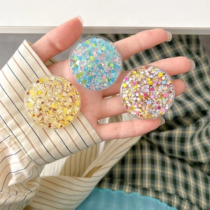 Macro detail of round retractable phone grip with colorful glitter and sequins