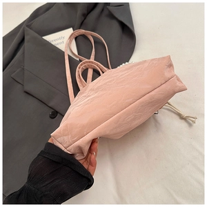 Detail of pink pleated fabric backpack featuring pearl chain accents and drawstring closure