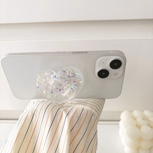 Macro shot of heart-shaped glitter phone grip with sequins on white phone case