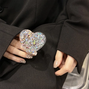 Close-up of heart-shaped glitter phone grip held against a black suit jacket