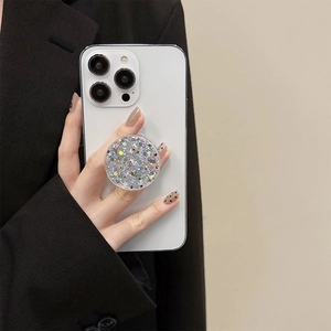 Close-up of a sparkling silver glitter retractable phone grip on a white smartphone
