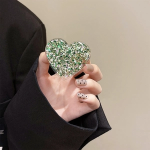 Detailed close-up of heart-shaped glitter phone grip with green and gold sequins