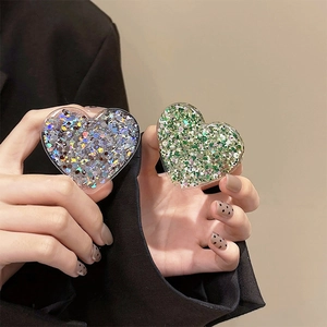 Close-up of a heart-shaped glitter phone grip featuring silver and green sequins
