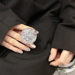Detail of a sparkling silver sequin phone grip held against a dark suit background