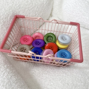 Close-up of colorful candy-colored button phone grips in a mini pink shopping basket