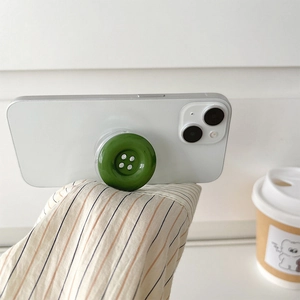 Close-up of a dark green button-shaped expandable phone grip on a white smartphone