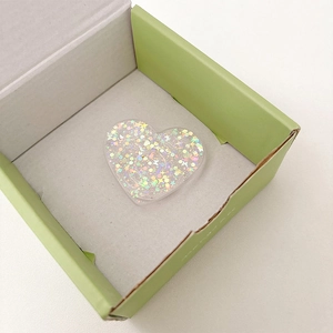 Close-up of heart-shaped glitter phone grip with colorful holographic sequins inside