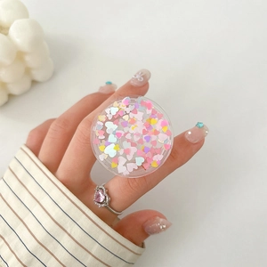 Detail view of round retractable phone grip with pink heart sequins and glitter effect