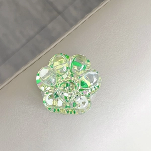 Macro view of a 3D cat paw phone grip with green iridescent sequins and glitter
