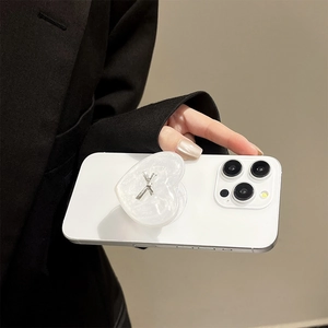 Close-up of heart-shaped phone grip with silver bow on a white smartphone
