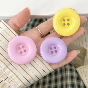 Detail of colorful pink, purple and yellow button-style phone grips held in hand