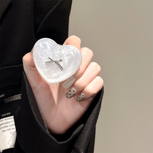 Close-up of a pearlescent white heart phone grip with a silver bow tie accent
