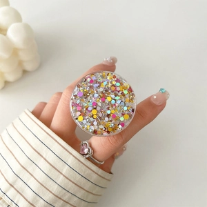 Close-up of glitter sequins phone grip holder held between fingers on a clean desk