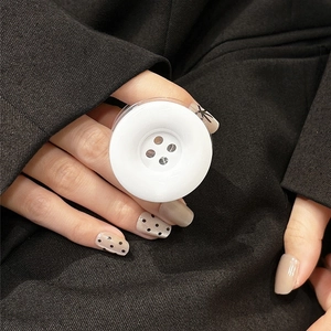 Close-up of a minimalist white button-shaped phone grip on a dark textured background