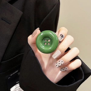Macro shot of a glossy forest green button-shaped phone socket held against a black suit